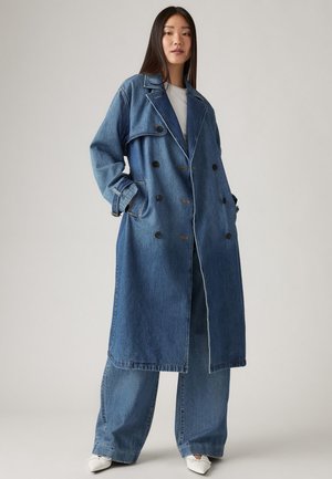 Denim trench coat in medium blue with double-breasted design, large pockets, and button accents. Wide legs with similar blue denim finish.