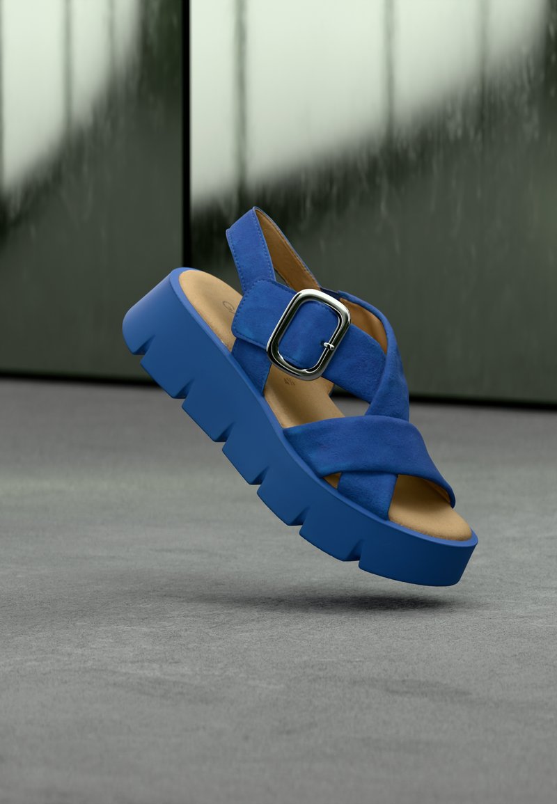 Sandales à plateforme bleu daim avec un design à brides croisées, boucle réglable et semelle épaisse texturée. Doublure intérieure neutre.