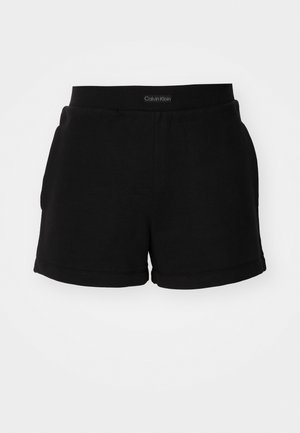 Pantalones cortos de algodón negros con una cinturilla acanalada, bolsillos laterales y un dobladillo redondeado. Logo exhibido en la cinturilla.