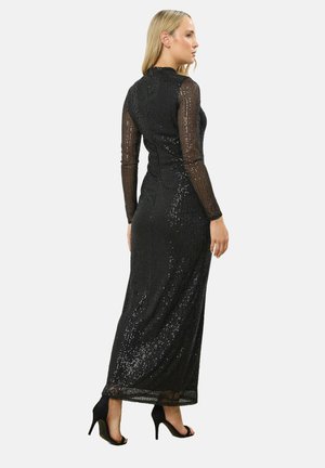 Sort glitrende aftenkjole med lange gennemsigtige sorte ærmer, tætsiddende liv og gulvlængde design. Har en subtil glans og glat tekstur.