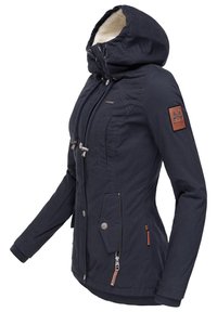 Navy blue waterproof jacket with a faux fur-lined hood, zip and button closures, chest and side pockets, and a textured leather logo patch.