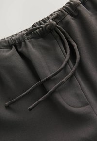Pantaloni jogger neri con vita regolabile, tessuto liscio, due tasche laterali e una vestibilità comoda.
