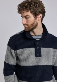 Pull en maille gaufrée à rayures bleu marine et gris, avec col châle et patte de boutonnage à trois boutons. Tissu texturé et poignets côtelés.