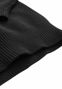 Čierna pletená látka s rebrovanou textúrou na leme. Mäkká a pružná, s hladkým povrchom a jemnými variáciami v hrúbke.