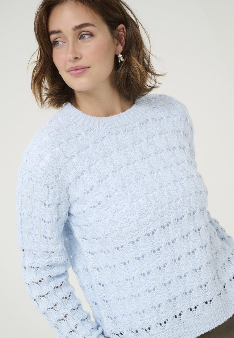 Helles blaues strickpullover mit einem strukturierten, offenen Maschenmuster; verfügt über einen runden Halsausschnitt und lange Ärmel.