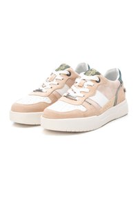 Zapatillas beige y blancas de ante y cuero, con puntera perforada, detalles verdes y una gruesa suela de goma blanca.