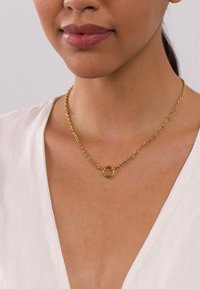 Collier en chaîne en or avec un pendentif circulaire à surface texturée, présentant un design de maillons classique. Style simple et élégant.
