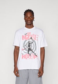 Witte katoenen T-shirt met een grafische print van een basketbalspeler,accentueert met roze en grijze tekst en cirkelpatronen.