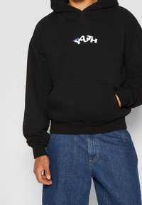 Felpa nera con cappuccio e tasca frontale, con un logo "YOUTH" in bianco e blu. Tessuto morbido, vestibilità ampia e polsini e orlo a coste.