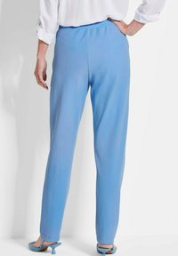Helle blaue Hose aus glattem Stoff, mit einem elastischen Bund und geradem Bein, kombiniert mit passenden Absatzsandalen.