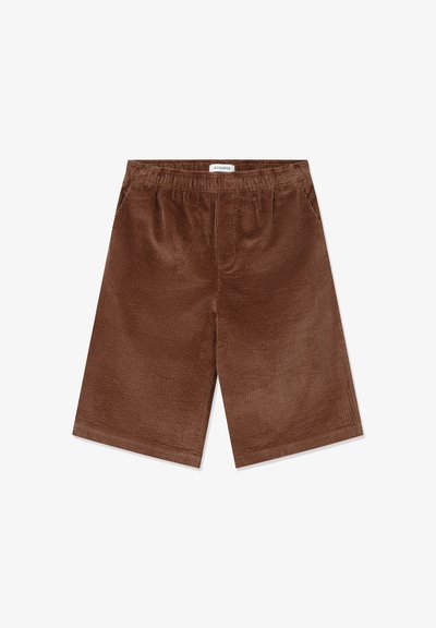 Ruskeat corduroy-shortsit, joissa on joustava vyötärö, polvipituinen leikkaus ja pystyribatoitu pinta. Tagi näkyvissä takana.