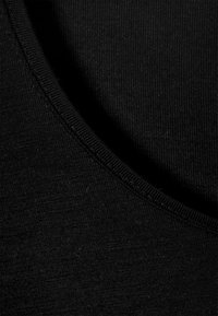 Black fabric close-up with a smooth texture, featuring a rounded neckline and unobtrusive seams. Material appears slightly textured.