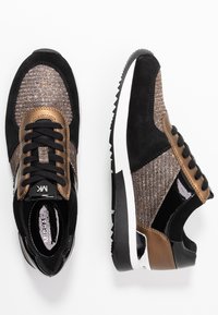 Zapatillas deportivas negras y bronce con una parte superior texturizada, acentos de ante y charol, punta redonda y una suela exterior negra texturizada.