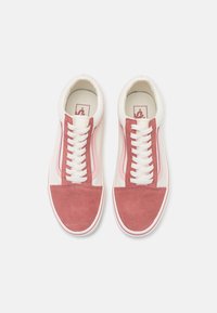 Rosa mockaskinn och vita canvas sneakers med en klassisk design, som har vita snören, gummisula och kontrasterande detaljer längs sidorna.