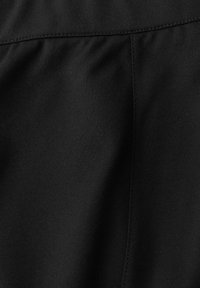 Tissu noir avec une texture lisse et mate. Présente une couture verticale avec un léger froncé sur le bord supérieur pour lui donner une forme.