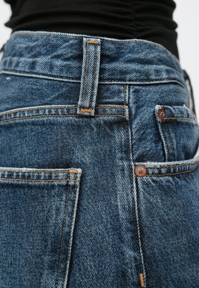 Τζιν παντελόνια σε σκούρο μπλε χρώμα με ορατές ραφές, κούμπωμα με κουμπί και τσέπες τύπου patch. Υφή υφάσματος με ελαφριά ξεθώριασμα.
