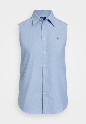 Gaiši zils bezpiedurkņu pogājams krekls no kokvilnas materiāla. Tam ir klasiskā apkakle un neliels izšūts logo uz krūtīm. Apakša ir noapaļota.