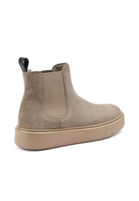 Botín de ante beige hasta el tobillo con paneles laterales elásticos, puntera redonda y una suela de goma beige. Cuenta con una pestaña en la parte posterior para facilitar su puesta.