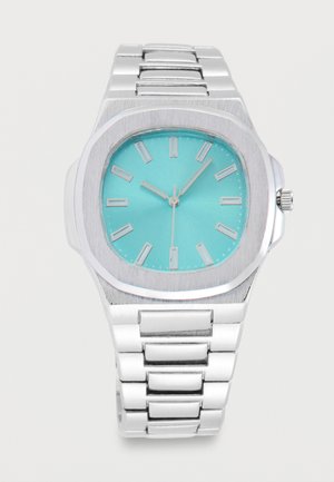 Orologio da polso in metallo argentato con quadrante turchese, indici argentati e tre lancette che segnano le 10:07:32.