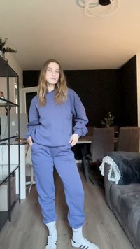 Lilla hættetrøje med sænkede skuldre og rib striber ved ærmerne, parret med matchende joggingbukser. Båret med hvide sokker med sorte striber.