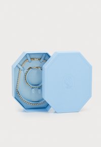Light blue octagonal jewelry box, textured exterior. Contains a bracelet and necklace with clear gems set in gold hardware.