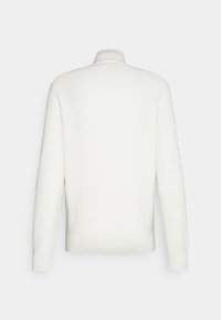 Pull en maille blanc à manches longues avec un col montant, des poignets côtelés et un ourlet côtelé, vu de dos sur un fond clair uni.