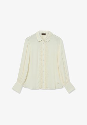 Kreemivärvi pluus pehmeast kangast, millel on ümmargune krae, nööpidega esiosa ja pitsdetailid keskel. Pikad varrukad mansettidega.