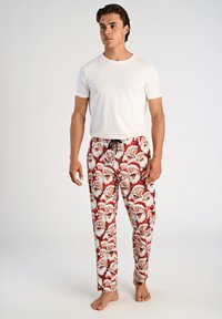 Witte korte mouwen t-shirt voor heren, gecombineerd met rode pyjamabroek met een herhalend patroon van het gezicht van de kerstman. Zachte stof, ontspannen pasvorm.