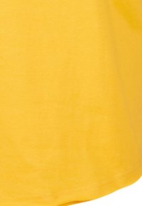 Gul bomulds T-shirt med en glat tekstur, korte ærmer og en buet kant, der har ren syning langs kanterne.