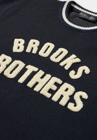 Námořnická modrá mikina s texturovanou krémovou výšivkou "BROOKS BROTHERS" napříč hrudníkem a pruhovaným žebrovaným výstřihem.