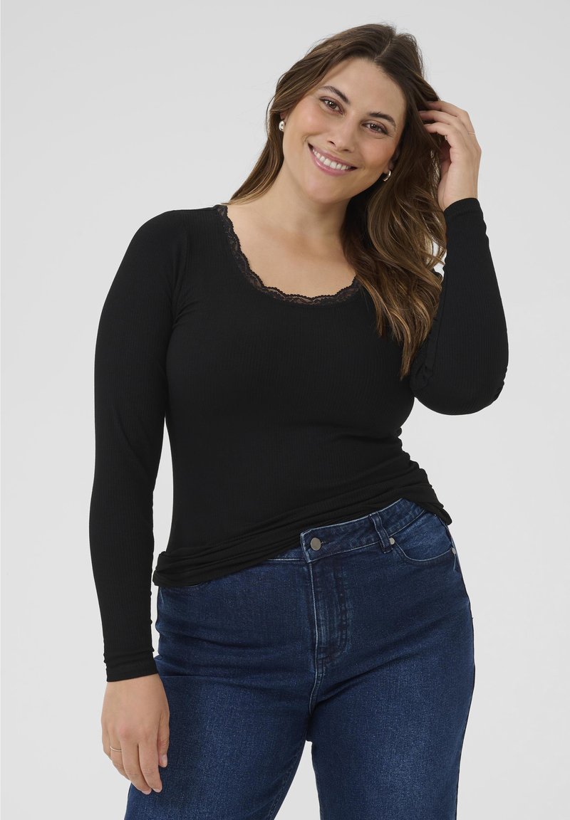 Top negro de manga larga con textura acanalada y escote en forma de lágrima con encaje. Combinado con jeans de mezclilla azul.