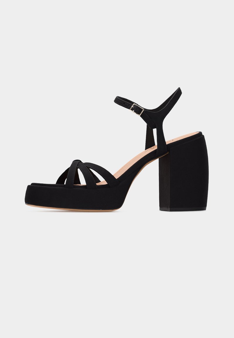 Μαύρο σανδάλι πλατφόρμα με χοντρό ψηλό τακούνι, τρεις μπροστινούς ιμάντες και ρυθμιζόμενο λουράκι αστραγάλου με ασημί πόρπη.