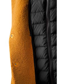 Orange fleece-yderside med en tekstureret overflade, kombineret med en sort quiltet inderside med lynlås og trykknapper.