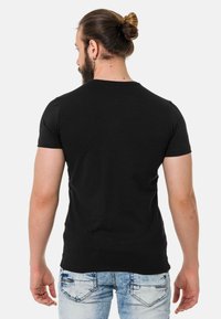 Schwarzes Baumwoll-T-Shirt mit kurzen Ärmeln, Rundhalsausschnitt und taillierter Silhouette, kombiniert mit hellen Jeans.