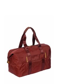 Borsa da viaggio in tessuto maroon con doppie maniglie, chiusura a cerniera e tasca frontale. Superficie testurizzata con dettagli in pelle.