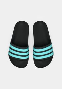 Zwarte slides met een gestructureerd oppervlak, voorzien van drie lichtblauwe strepen en twee zwarte strepen over het bovendeel. Platte zool.