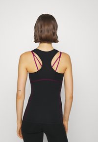 Svart atletisk linne med en figurnära design, som har flera tunna lila remmar och en slät textur. Inga synliga mönster eller utsmyckningar.