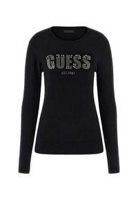 Zwarte trui met een ronde hals, lange mouwen en geribbelde manchetten. Bevat het "GUESS" logo in zilveren studs en "EST.1981" eronder.