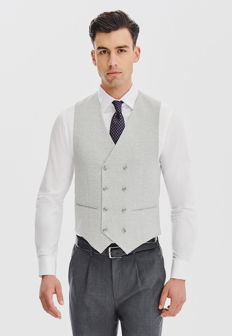 Jasnoszara, teksturowana kamizelka w kształcie litery V, z podwójnymi guzikami i dopasowanym krojem, noszona na białej koszuli i szarych spodniach.