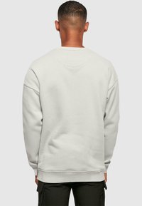 Lys grå sweatshirt med afslappet pasform, rund hals og ribbede manchetter. Har en blød tekstur og minimalistisk design.