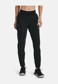 Pantalones deportivos negros con cinturilla elástica, piernas estrechas y una tela suave y ligera. Presenta un pequeño logo en el muslo izquierdo.