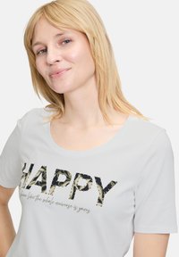 Lichtgrijs T-shirt met een ronde halslijn, voorzien van een "HAPPY" graphic in textuur- en patroonletters met daaronder een subtiele script.