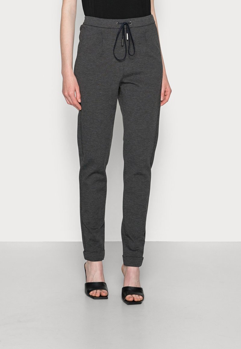 Šedé kostkované tepláky s šňůrkou v pase a elastickými manžetami. Materiál je lehký a má texturovaný vzor. Design s plochým předním dílem.