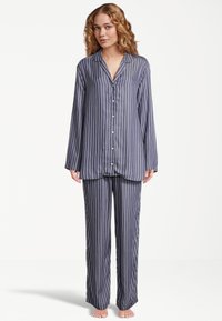 Mörkblå randig pyjamasuppsättning, bestående av en skjorta med knappar och långa ärmar samt matchande byxor, tillverkad i ett smidigt tyg med mjuk textur.