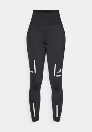 Leggings neri con un alto punto vita, realizzati in materiale elasticizzato. Presentano strisce bianche verticali e un logo vicino alla caviglia e alla parte superiore della gamba.