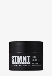 Pot noir de STMNT Statement Grooming Goods Dry Clay, 100 ml, avec un texte blanc en gras sur un fond blanc uni.