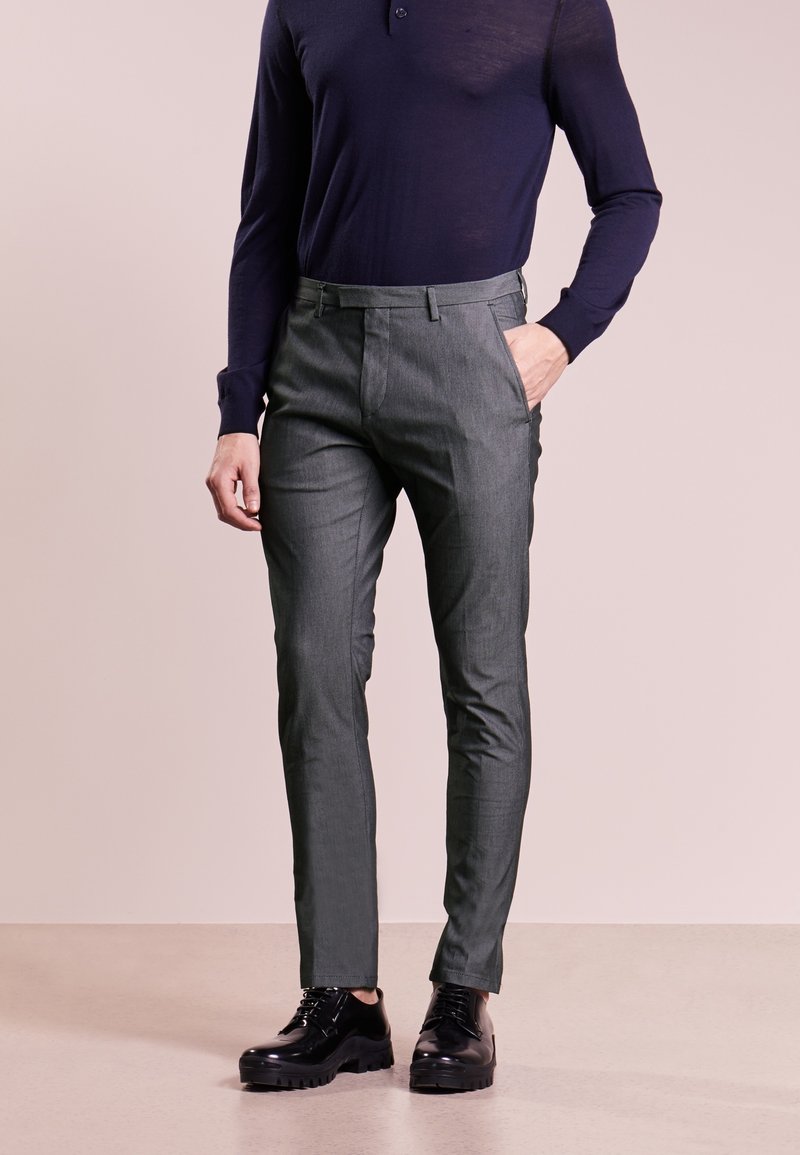 Pantalon gris sur mesure avec une finition texturée, doté de passants pour ceinture et de poches latérales, assorti à des chaussures habillées noires et une chemise à manches longues bleu marine.
