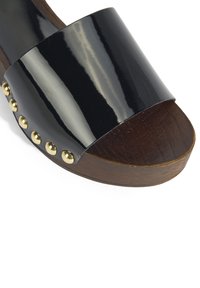 Zwarte gepolijste schuif sandaal met een brede band, houten basis en gouden studs langs de zijkant. Glad materiaal met een glanzende afwerking.