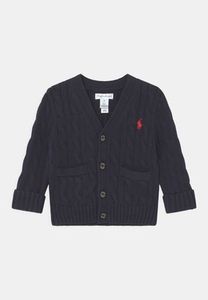 Cardigan bleu marine en maille torsadée avec boutons sur le devant, deux poches, manches avec poignets et logo rouge brodé sur la poitrine gauche.