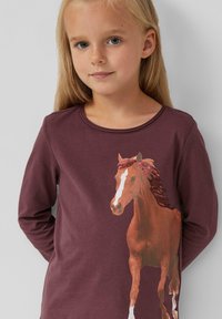 Bordeauxfarbenes langärmliges Shirt mit einem bedruckten braunen Pferd und einem weißen Streifen. Weicher Stoff mit Rundhalsausschnitt und minimalen Texturdetails.